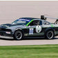 A black race car with the number 89 on the door, adorned with the "Chicken N Pickle" logo and graphics, speeds down a racetrack. The car is equipped with a 9livesracing Mustang Big Wang Kit '05-09 S197 aluminum wing for superior downforce adjustments and features various sponsor decals. Grass is visible in the foreground.