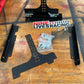 The image displays a disassembled Nine Lives Racing Chassis Mount Splitter Quick Release Kit laid out on a wooden table. Visible components include black metal brackets, splitter mounts, a perforated metal strip, screws in a plastic pouch, and a Nine Lives Racing logo sticker. A red container is partially visible in the corner.