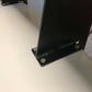 Close-up image of the bottom part of a black metal bracket securely fastened to a shiny, reflective white surface with several silver bolts. The bracket is part of the 9livesracing 3-Series Big Wang Kit '90-00 E36 extruded aluminum wing structure that extends upwards out of the frame.