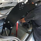 A person wearing a black shirt and cap installs the Honda S2000 Chassis Pylons - Pylons only with aluminum hardware from 9livesracing in the trunk of a vehicle. The trunk lid is open, revealing various tools and components.