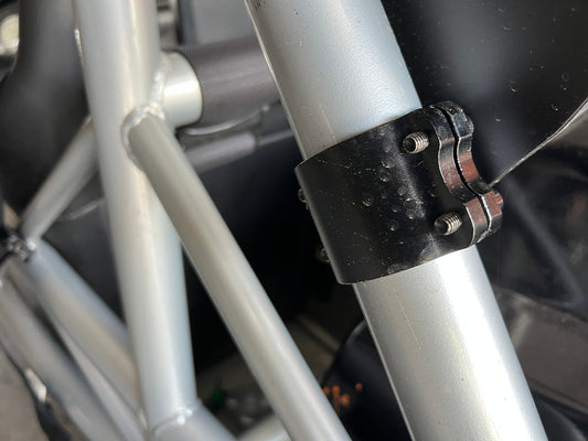 A close-up view of the Exocet v2 Big Wang Kit by 9livesracing showcases light gray cylindrical bars connected by a black clamp with bolts. The industrial setting emphasizes the robust, utilitarian construction that mirrors the down-force principles seen in GT3 performance engineering.