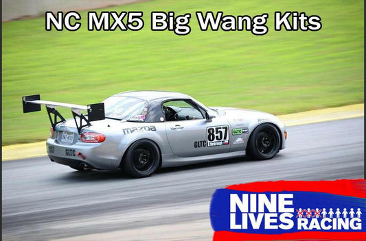 A silver Mazda MX-5 race car with the number 857 and various sponsor stickers on its body is driving on a racetrack. The car, featuring a Miata Big Wang Kit '06-15 NC *V1* aluminum wing from 9livesracing, showcases the text "NC MX5 Big Wang Kits" at the top and a "9livesracing" logo at the bottom.