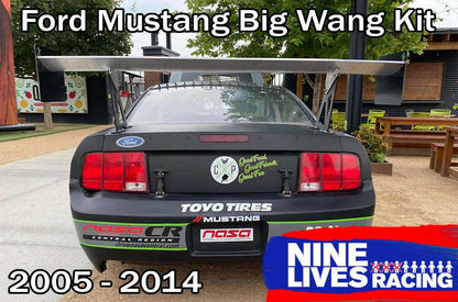 A black Ford Mustang race car with a large rear wing, adorned with sponsor decals. The text at the top reads "Mustang Big Wang Kit '05-09 S197," and at the bottom, "2005 - 2014." The "9livesracing" logo is located at the bottom right corner, along with other sponsor names and logos on the car.