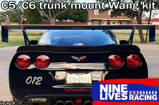 Photograph of a black Chevrolet Corvette featuring a Texas license plate JDD-2441 and adorned with a substantial Nine Lives Racing aluminum wing mounted on the trunk. The vehicle displays the number "012" on its bumper. The top of the image showcases "Corvette Big Wang Trunk Mount Kit '97-13 C5/6," while the bottom right corner bears the 9livesracing logo.