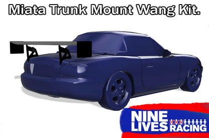 A blue sports car featuring a large rear wing is displayed, showcasing the "Miata Big Wang Kit '90-05 NA/NB" for increased down-force. Text reads "Miata Trunk Mount Wang Kit." The image includes the "9livesracing" logo in the bottom right corner, proudly highlighting its American-made quality.