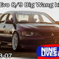 A dark-colored Mitsubishi Lancer Evolution 8/9 is featured with an "Evolution 8/9 Big Wang kit ’03-07 CT9A" and aluminum wings. The car showcases white wheels, various stickers including "Tire Rack," and a substantial rear wing to boost down-force. Text reads "Evolution 8/9 Big Wang kit ’03-07 CT9A," "9livesracing," and "2003-07.