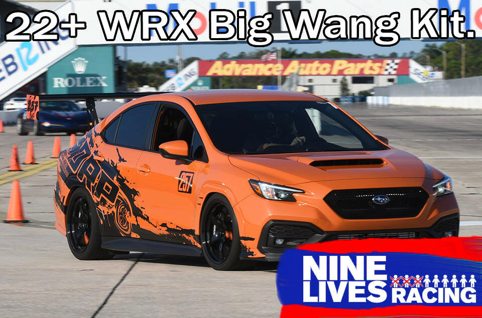 An orange Subaru Impreza STI, sporting the '2022 - current Big Wang Kit from 9livesracing, zips through a racetrack adorned with black decals and skillfully navigates around orange cones. The car demonstrates optimal downforce adjustments for perfect stability. Overlays feature "Subaru Impreza STI Big Wang kit '2022 - current" and the "9livesracing" logo on the bottom right.