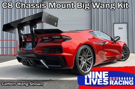 A red sports car, featuring a large black carbon fiber rear wing, is parked in front of a corrugated metal building with a white door numbered 1114. Text on the image reads: "Corvette Big Wang Chassis Mount ’2020 C8" and "9livesracing." This setup maximizes down-force while optimizing the lift-to-drag ratio.
