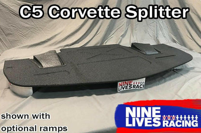 The Corvette Rocket Nose Splitter ’97-04 C5 by 9livesracing, CNC cut for precision, is displayed resting on a gray surface. The black splitter features two optional ramps and prominently showcases the "Nine Lives Racing" logo with a blue and red design on the lower right side. Text at the top reads, "C5 Corvette Splitter.