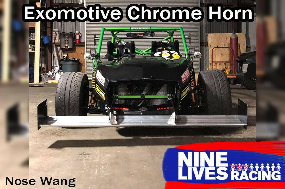 A green race car sits proudly in a garage, equipped with an Exocet Chrome Horn Nose Wang Kit and striking aluminum wings. It features a large front splitter and brightly colored decals. Text on the image reads "Exocet Chrome Horn" and "9livesracing," with "Nose Wang" visible at the bottom left.