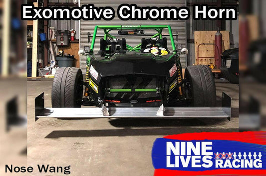 A green race car sits proudly in a garage, equipped with an Exocet Chrome Horn Nose Wang Kit and striking aluminum wings. It features a large front splitter and brightly colored decals. Text on the image reads "Exocet Chrome Horn" and "9livesracing," with "Nose Wang" visible at the bottom left.