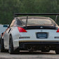 Rear view of a white sports car equipped with the 350z Big Wang Kit '02-08 Z33 from 9livesracing, showcasing extruded aluminum wings and black detailing. The car sports a license plate reading "EAD H8R" and is parked on a concrete surface with greenery in the background.